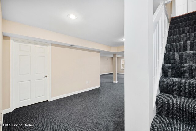 finished below grade area featuring stairs, dark colored carpet, recessed lighting, and baseboards