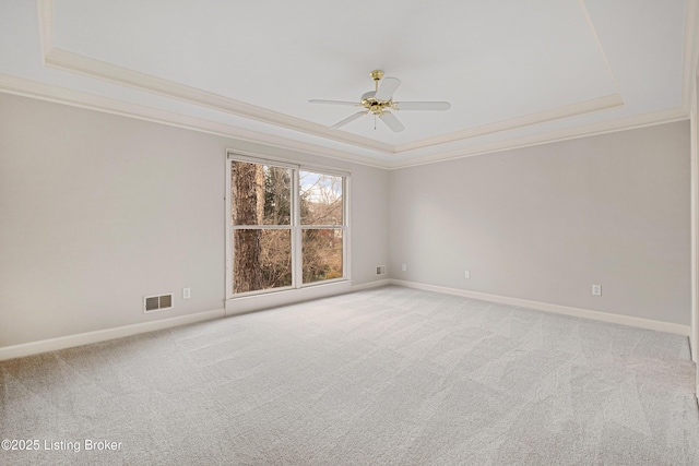 spare room featuring baseboards, visible vents, a raised ceiling, light colored carpet, and ornamental molding