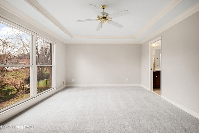 unfurnished room with light carpet, a tray ceiling, ornamental molding, and baseboards