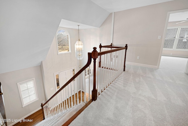 staircase featuring high vaulted ceiling, baseboards, a chandelier, and a wealth of natural light