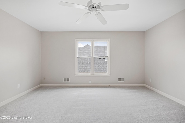 empty room featuring light colored carpet, visible vents, and ceiling fan