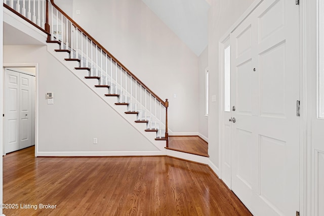 foyer with stairs, lofted ceiling, baseboards, and wood finished floors