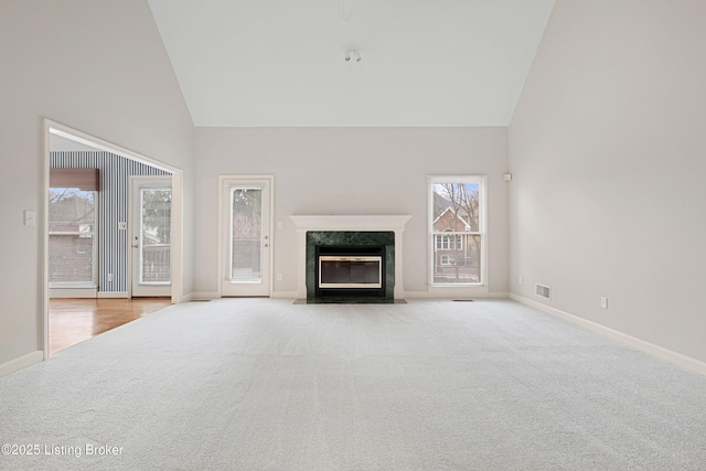 unfurnished living room with visible vents, high vaulted ceiling, carpet, and a high end fireplace