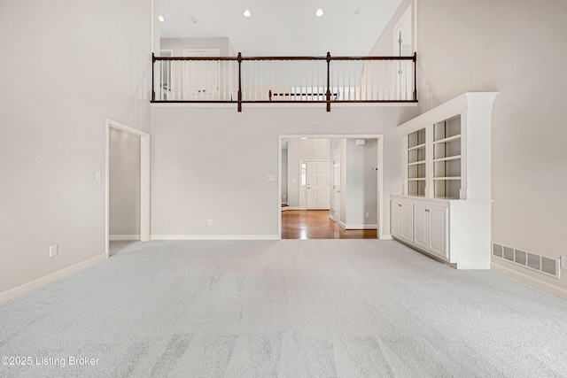 unfurnished living room with carpet floors, recessed lighting, visible vents, and baseboards