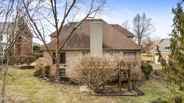 back of house with a shingled roof, a lawn, and brick siding