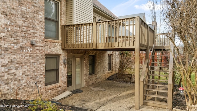 exterior space with a patio area, a wooden deck, stairway, and brick siding