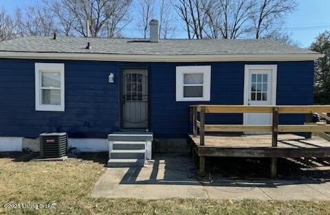 back of property with a wooden deck, roof with shingles, and central AC