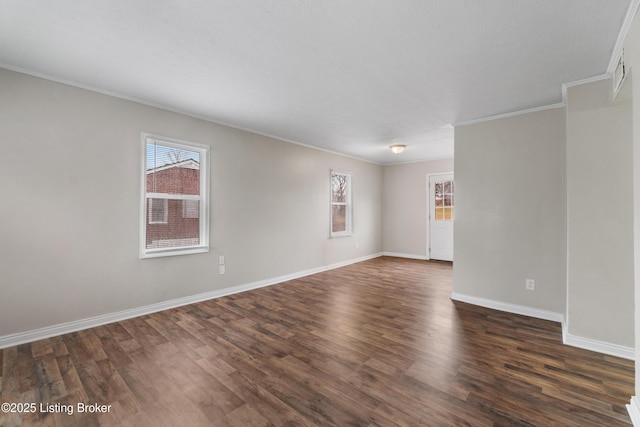 spare room with dark wood-type flooring, crown molding, and baseboards