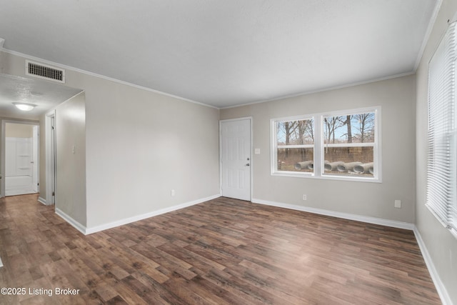 spare room with visible vents, baseboards, dark wood finished floors, and ornamental molding