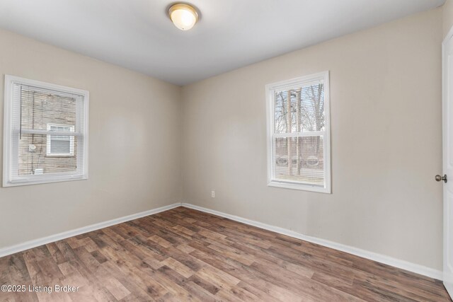 spare room featuring baseboards and wood finished floors