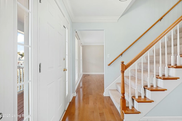 foyer entrance with ornamental molding, stairway, light wood-style flooring, and baseboards