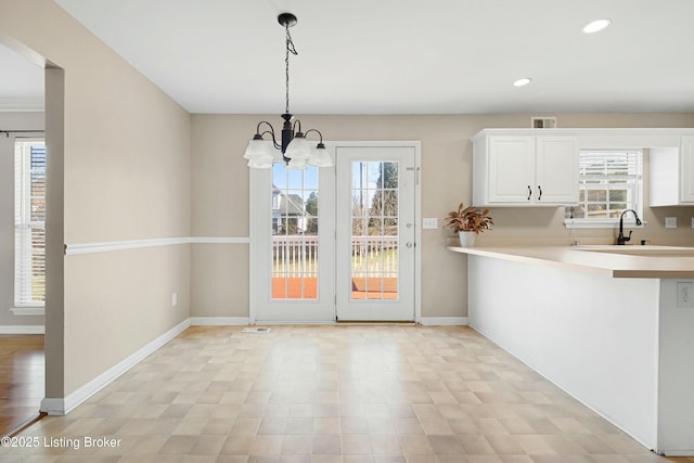 unfurnished dining area featuring visible vents, baseboards, a sink, a notable chandelier, and recessed lighting