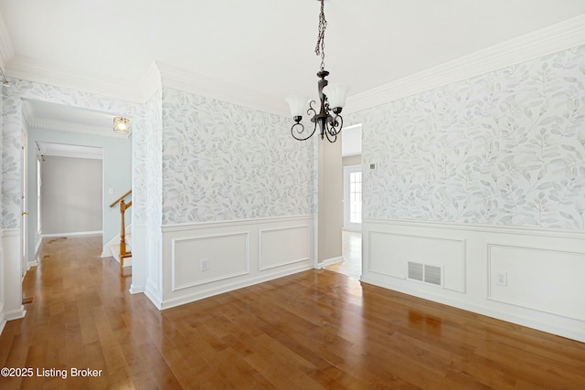 unfurnished dining area featuring wallpapered walls, stairs, visible vents, and wood finished floors