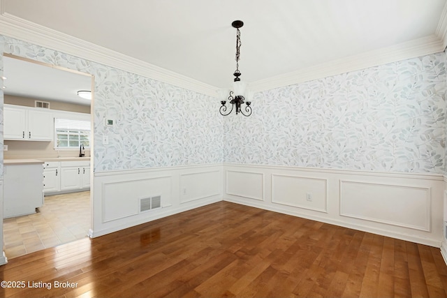 unfurnished dining area with hardwood / wood-style floors, visible vents, and wallpapered walls