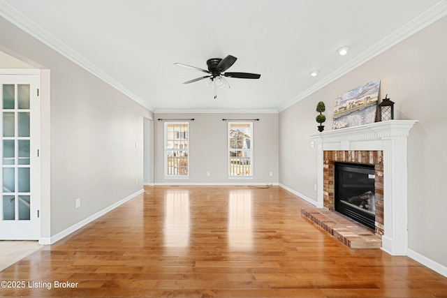 unfurnished living room featuring baseboards, light wood-style flooring, ceiling fan, ornamental molding, and a fireplace