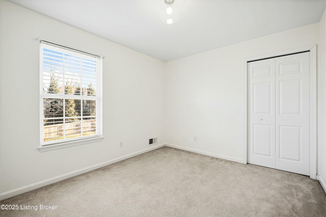 unfurnished bedroom with carpet floors, a closet, visible vents, and baseboards