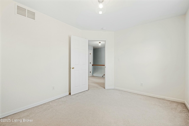 carpeted spare room featuring baseboards and visible vents