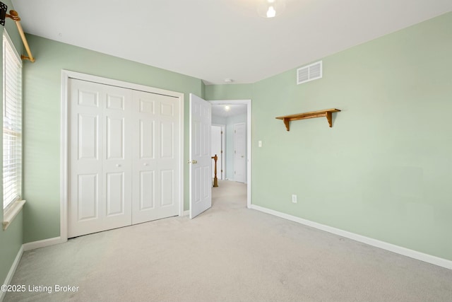 unfurnished bedroom with a closet, carpet flooring, visible vents, and baseboards