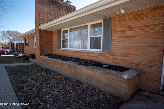 view of home's exterior with a chimney and brick siding