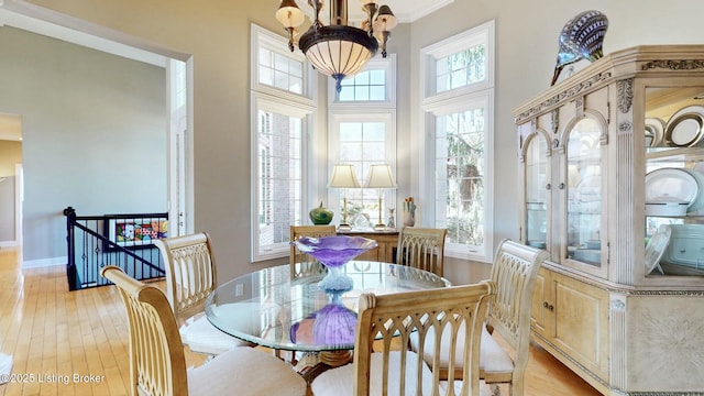 dining area with a healthy amount of sunlight, baseboards, light wood-type flooring, and an inviting chandelier