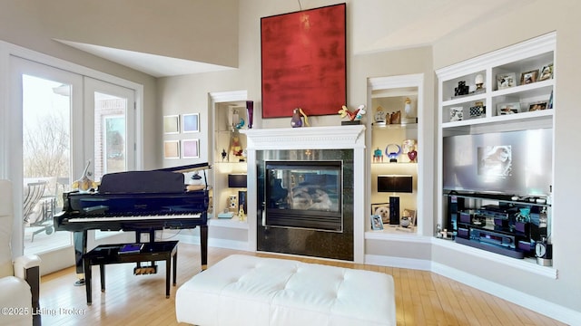 living area with built in features, baseboards, wood finished floors, and a fireplace