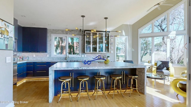 kitchen with backsplash, a center island, a breakfast bar, light wood-type flooring, and blue cabinets