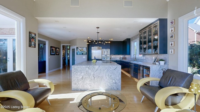 kitchen with glass insert cabinets, built in refrigerator, tasteful backsplash, and light wood finished floors