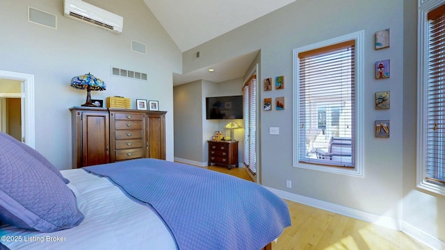 bedroom featuring visible vents, baseboards, a wall unit AC, and wood finished floors