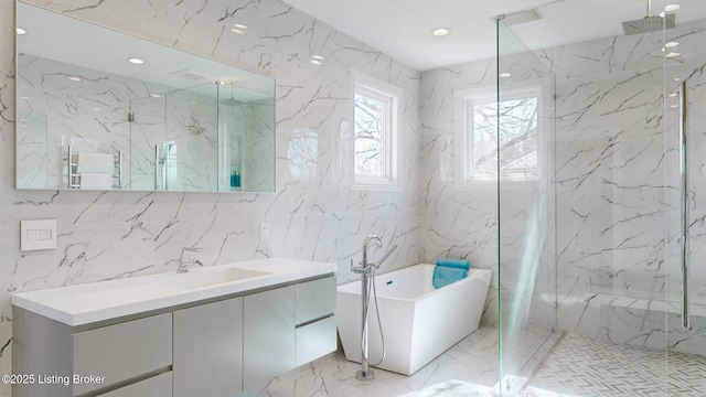 full bath featuring a marble finish shower, stone wall, a freestanding bath, and vanity