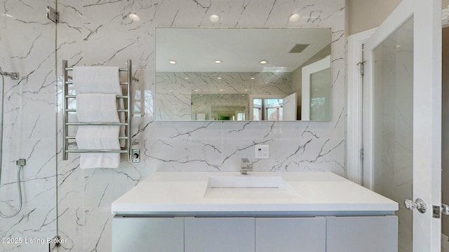 bathroom featuring a marble finish shower, tile walls, vanity, and radiator heating unit