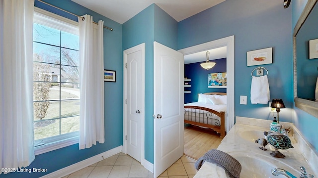 ensuite bathroom with tile patterned floors, baseboards, plenty of natural light, and ensuite bathroom