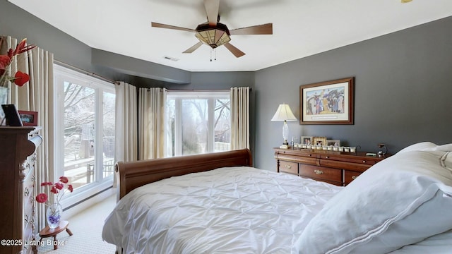 carpeted bedroom featuring visible vents, multiple windows, ceiling fan, and access to outside