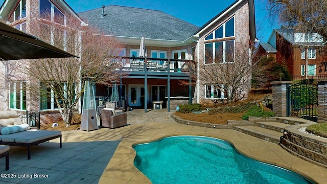 outdoor pool with a wooden deck and a patio