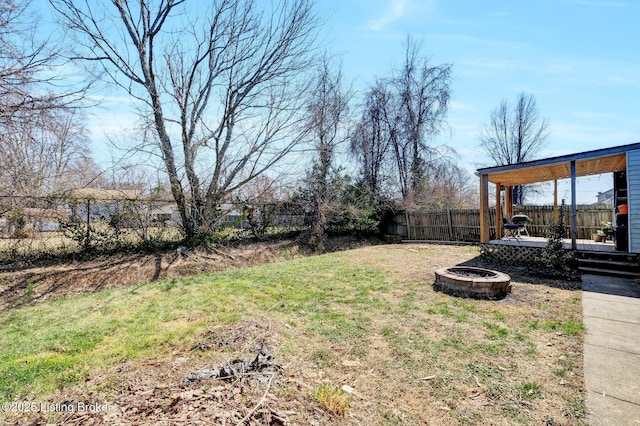 view of yard with a fire pit, fence, and a wooden deck