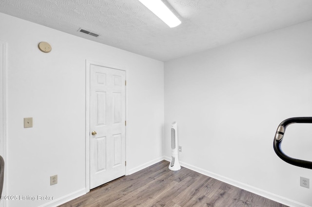 laundry room with visible vents, wood finished floors, baseboards, and a textured ceiling