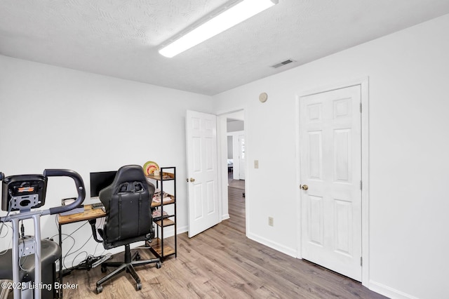 office space with visible vents, wood finished floors, baseboards, and a textured ceiling