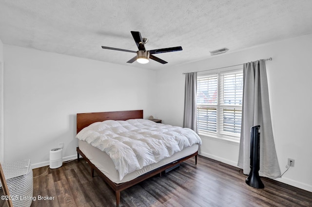 bedroom with visible vents, a textured ceiling, baseboards, and wood finished floors