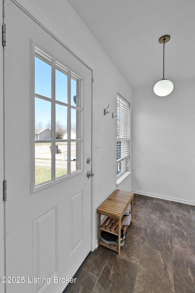 doorway featuring stone finish floor and baseboards