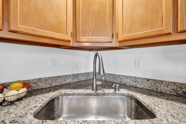 interior details with light stone countertops, light brown cabinets, and a sink