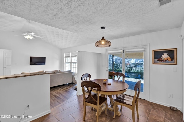 dining area with visible vents, lofted ceiling, a textured ceiling, and a ceiling fan