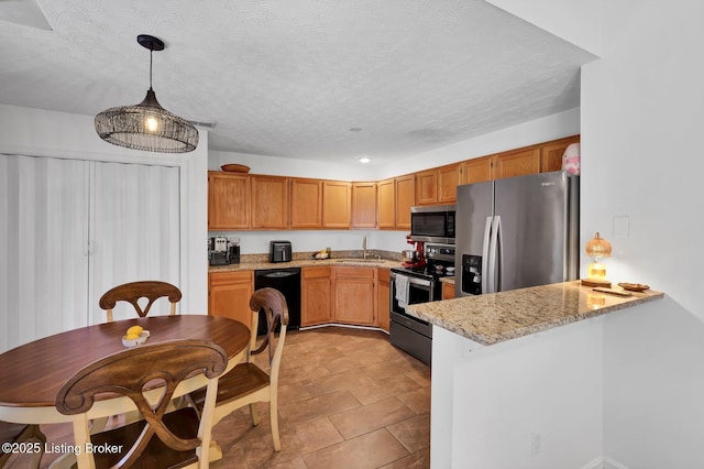 kitchen featuring a sink, decorative light fixtures, a textured ceiling, appliances with stainless steel finishes, and a peninsula