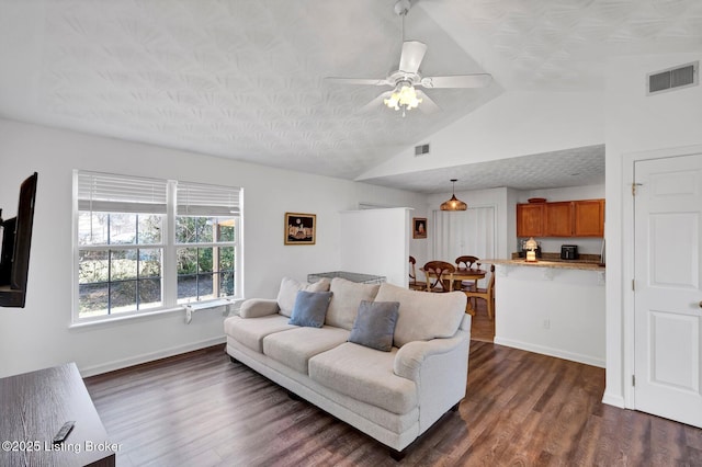 living room featuring visible vents, baseboards, dark wood-style floors, and vaulted ceiling