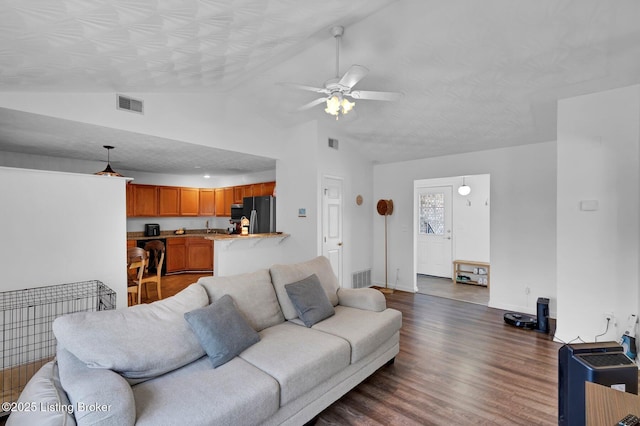 living area featuring lofted ceiling, dark wood-style floors, and visible vents