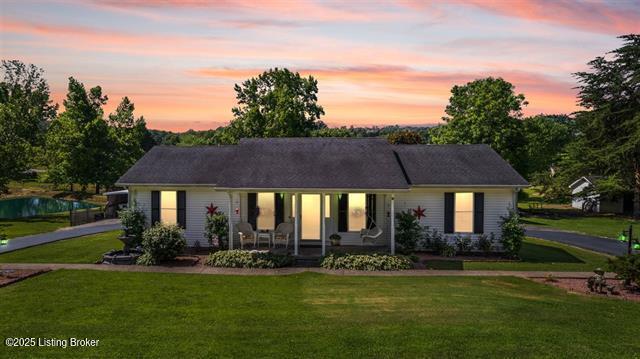 ranch-style home featuring covered porch and a lawn