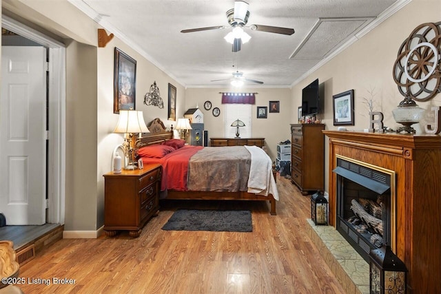 bedroom featuring light wood finished floors, a fireplace with flush hearth, visible vents, and ornamental molding