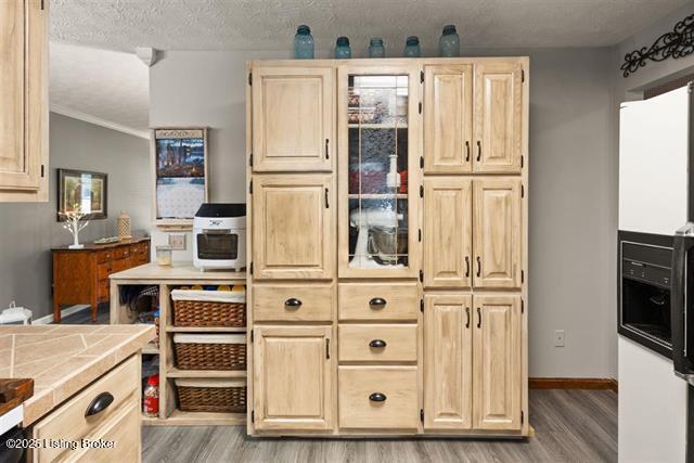 kitchen with tile countertops, light wood-style flooring, light brown cabinets, a textured ceiling, and baseboards