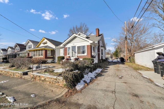 view of front of home with brick siding, driveway, and a chimney