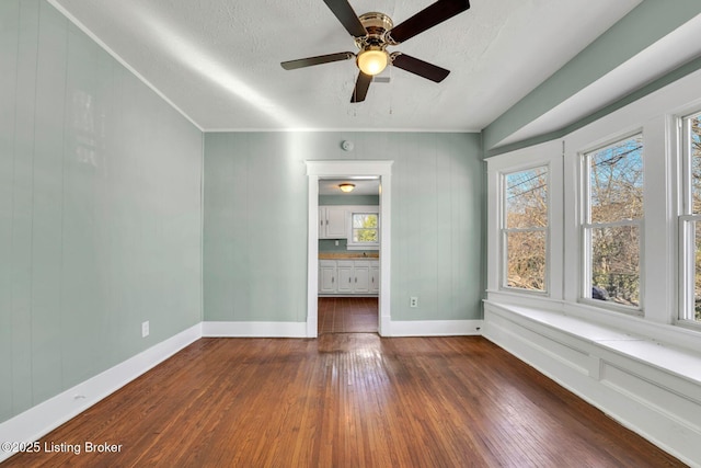 empty room with a wealth of natural light, a textured ceiling, and hardwood / wood-style floors