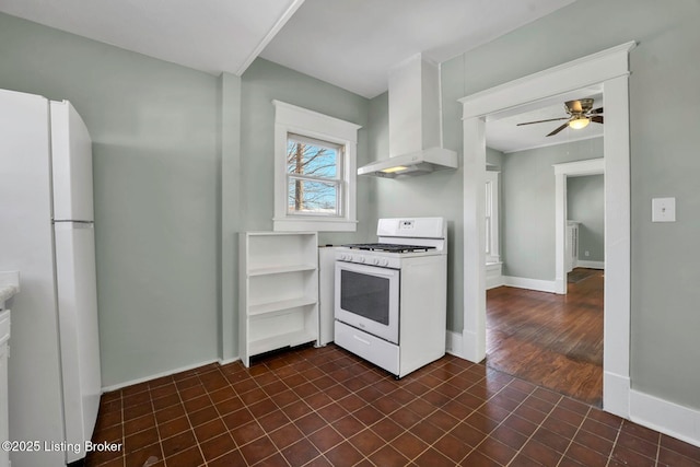 kitchen with white appliances, wall chimney exhaust hood, baseboards, and ceiling fan