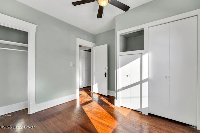 unfurnished bedroom featuring baseboards, hardwood / wood-style floors, and multiple closets